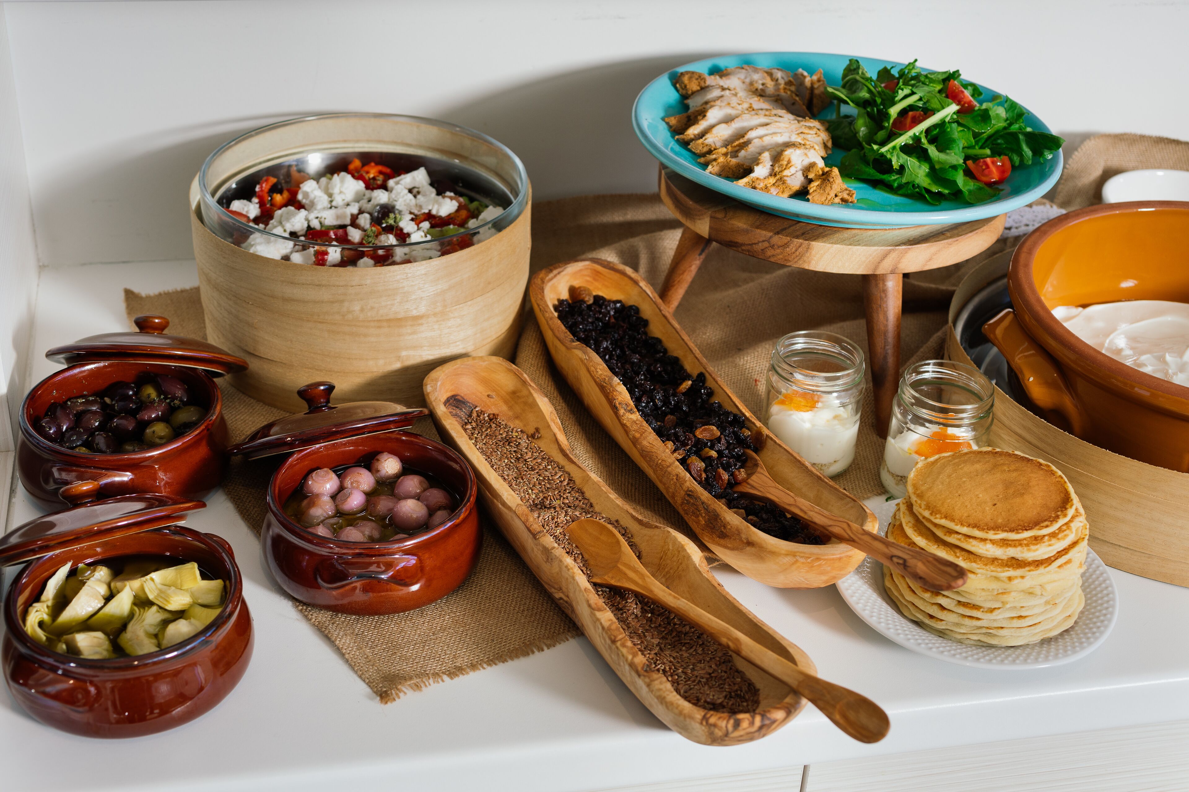 A variety of food items and wooden serving dishes on a table.