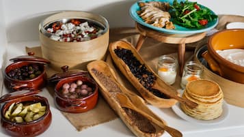 A variety of food items and wooden serving dishes on a table.