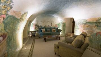 Una sala de estar acogedora y semicircular, con un mural en las paredes, un sofá azul, un sillón marrón y una mesa de centro.
