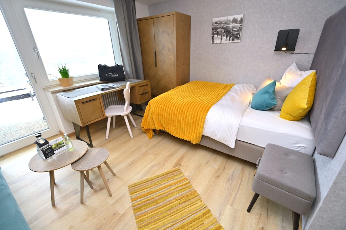 Ein modernes Hotelzimmer mit einem Bett, einem Schreibtisch, einem Stuhl, einem kleinen Tisch und einer Couch.