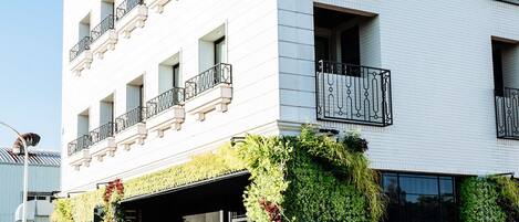 Un hotel de varios pisos con balcones, una entrada cubierta y jardines verticales.