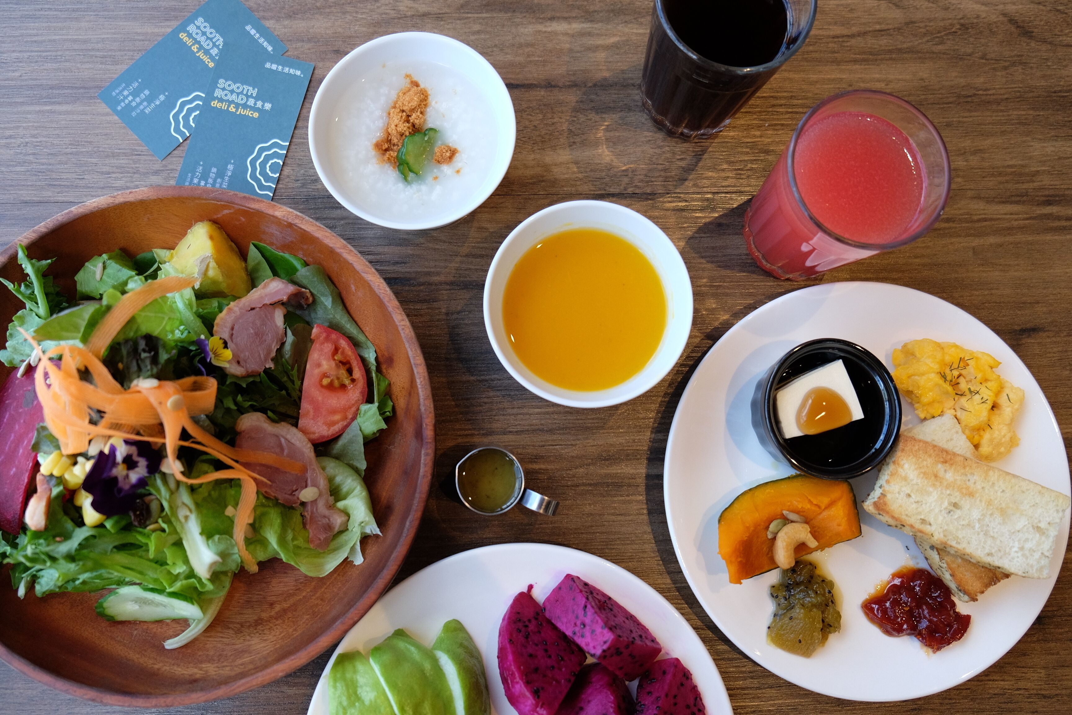 Una mesa con diversos platos, incluyendo una ensalada, sopa y un plato con pan y fruta.