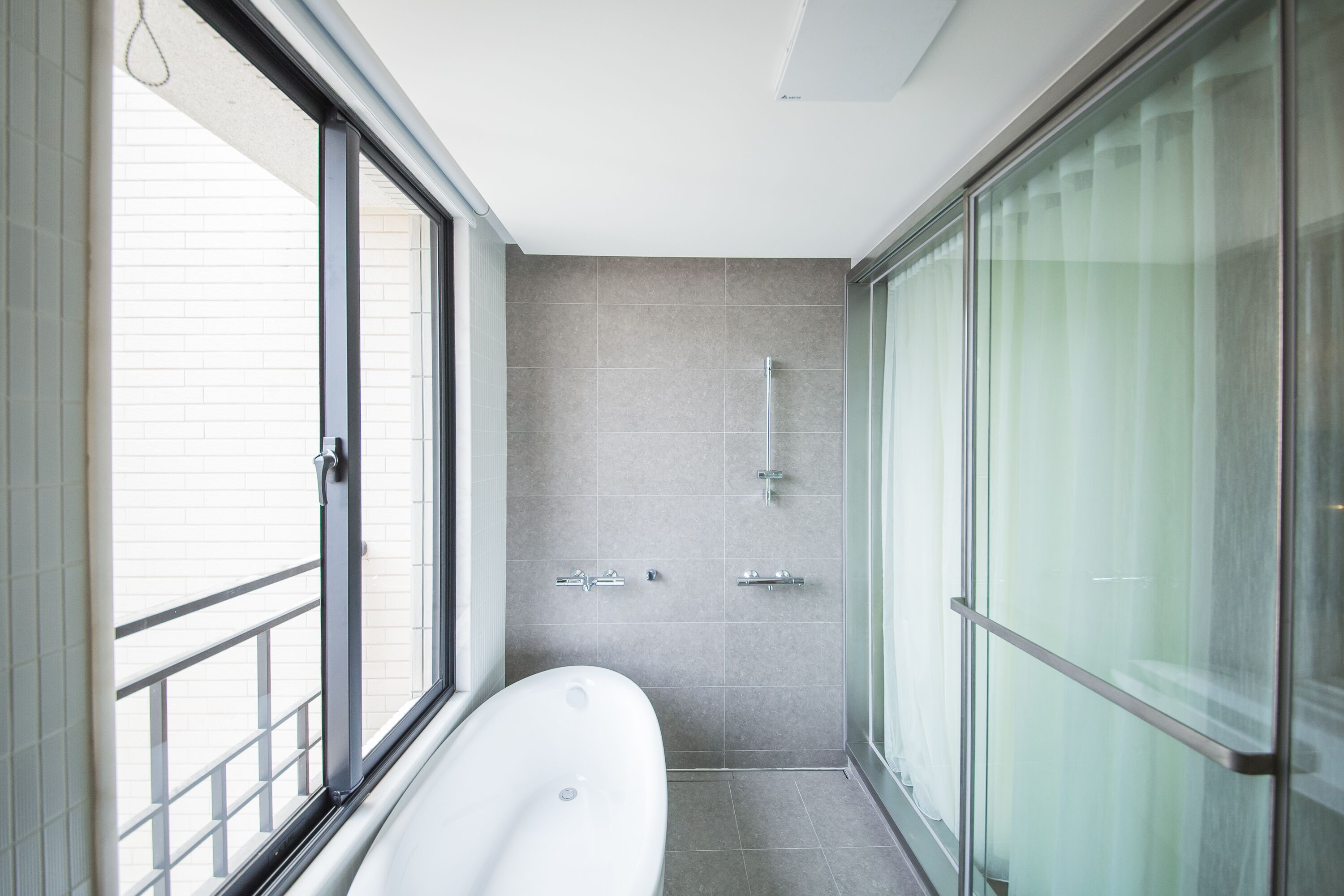 A modern bathroom with a freestanding bathtub, a glass shower enclosure, and a large window providing natural light.