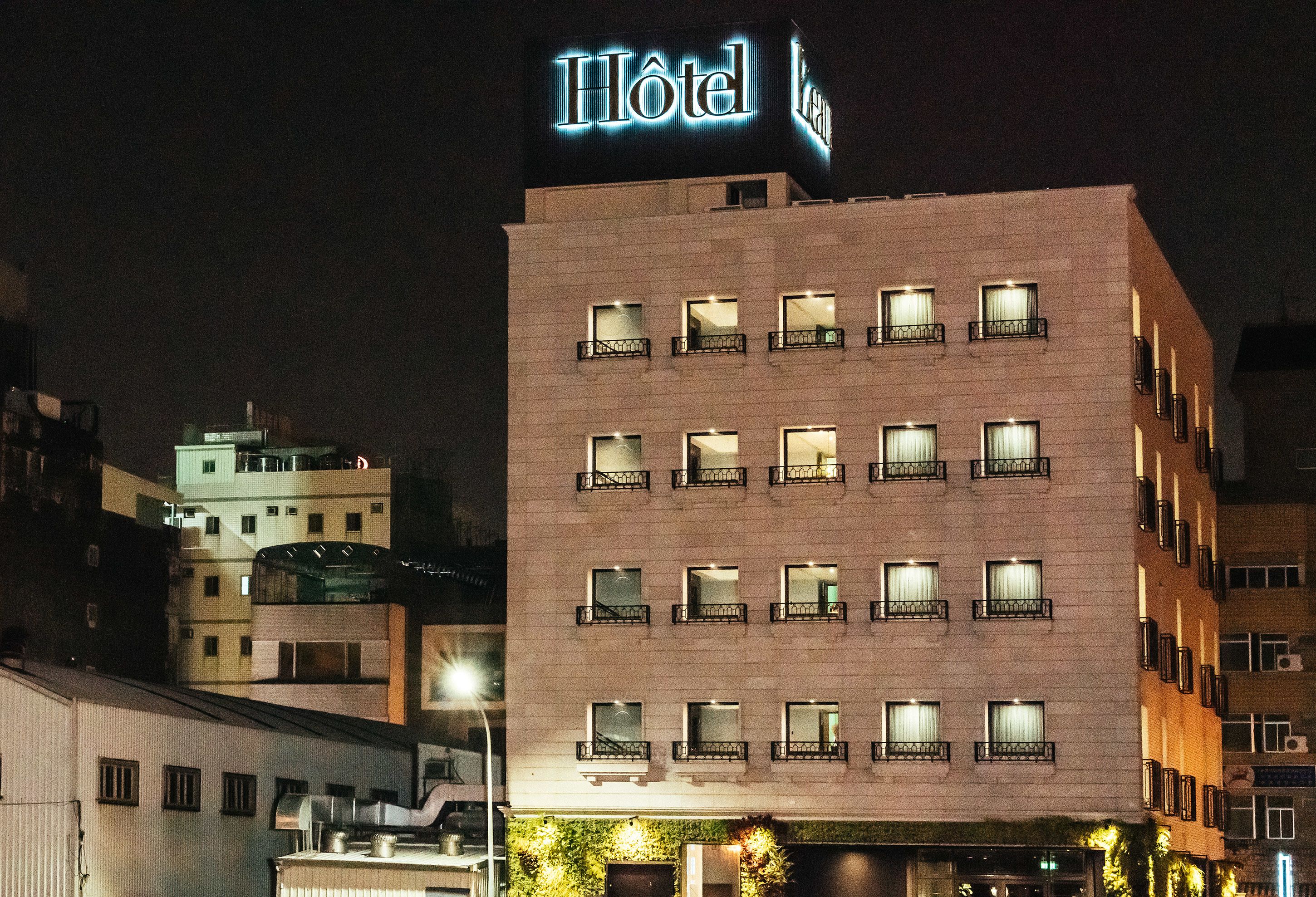 A hotel building with multiple floors, balconies, and a prominent illuminated sign.