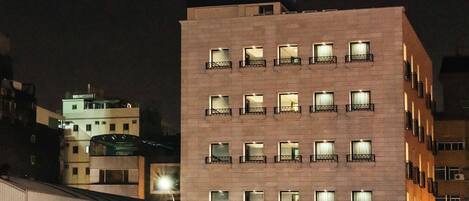 A hotel building with multiple floors, balconies, and a prominent illuminated sign.