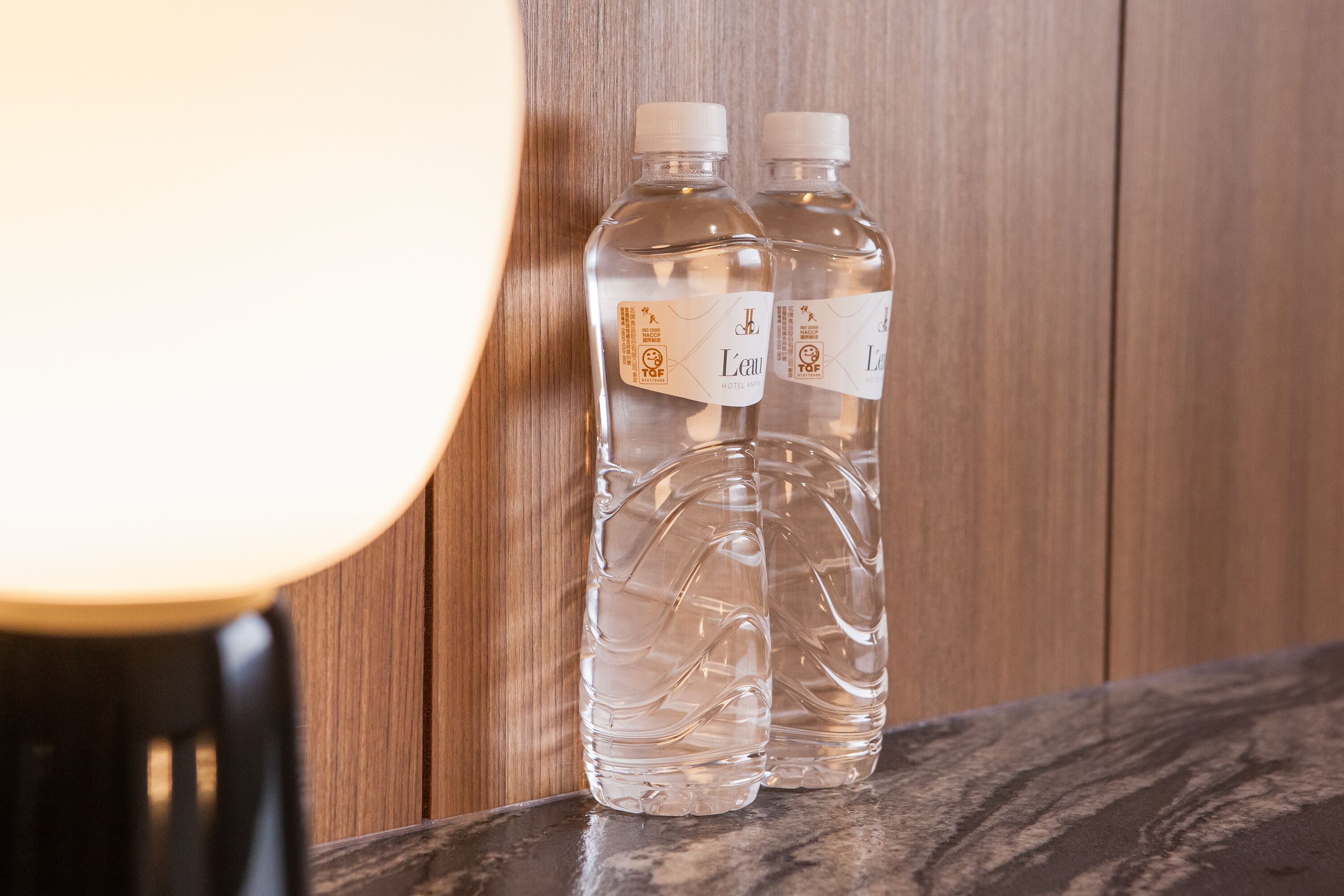 Two clear water bottles with labels on a wooden surface.