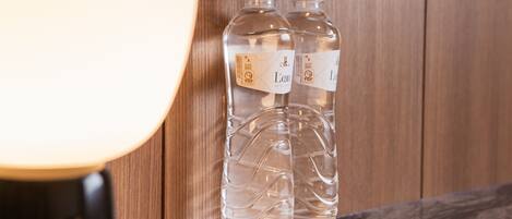 Two clear water bottles with labels on a wooden surface.