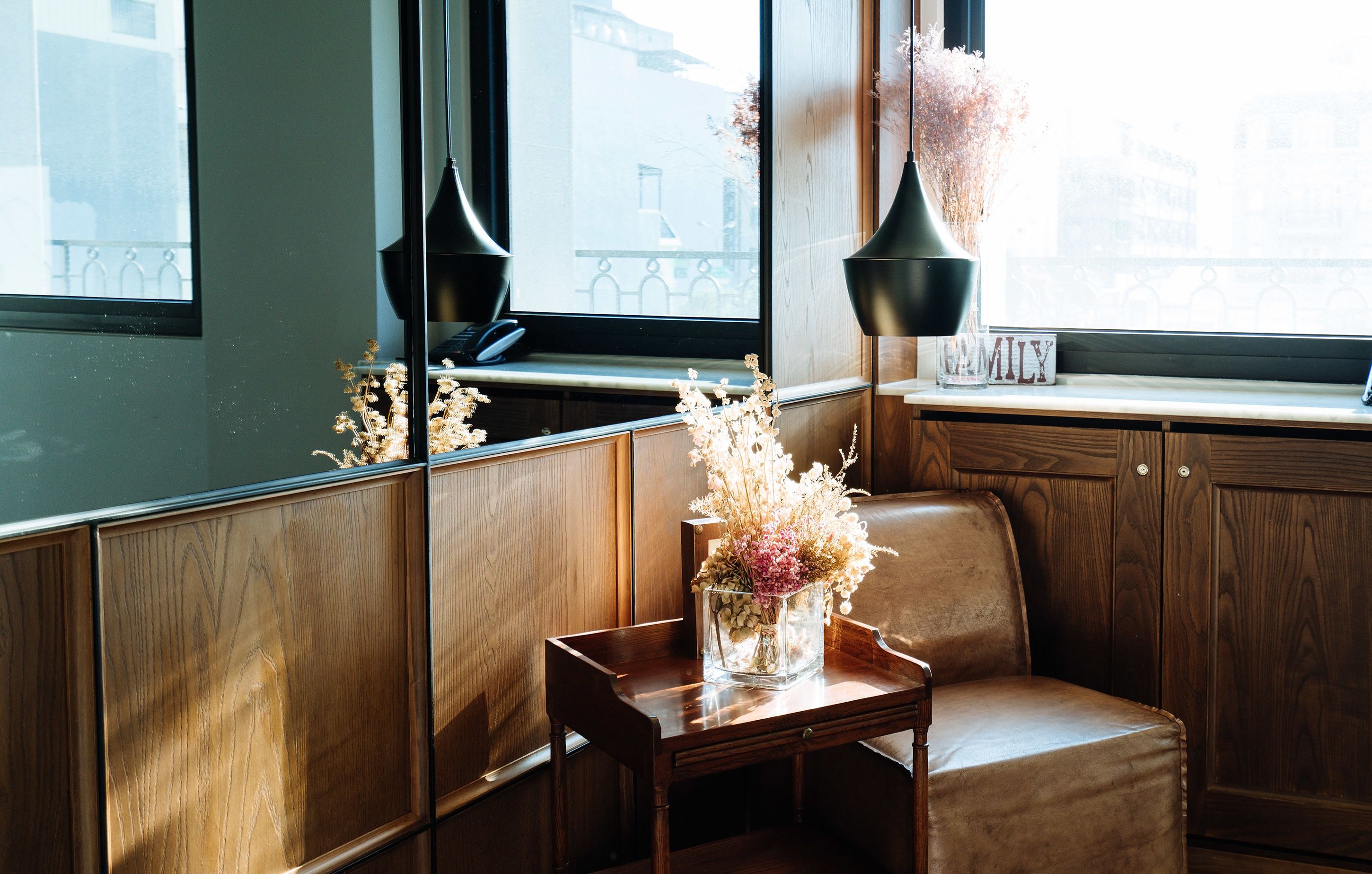 A corner seating area with a wooden bench and a small table with a vase of dried flowers.