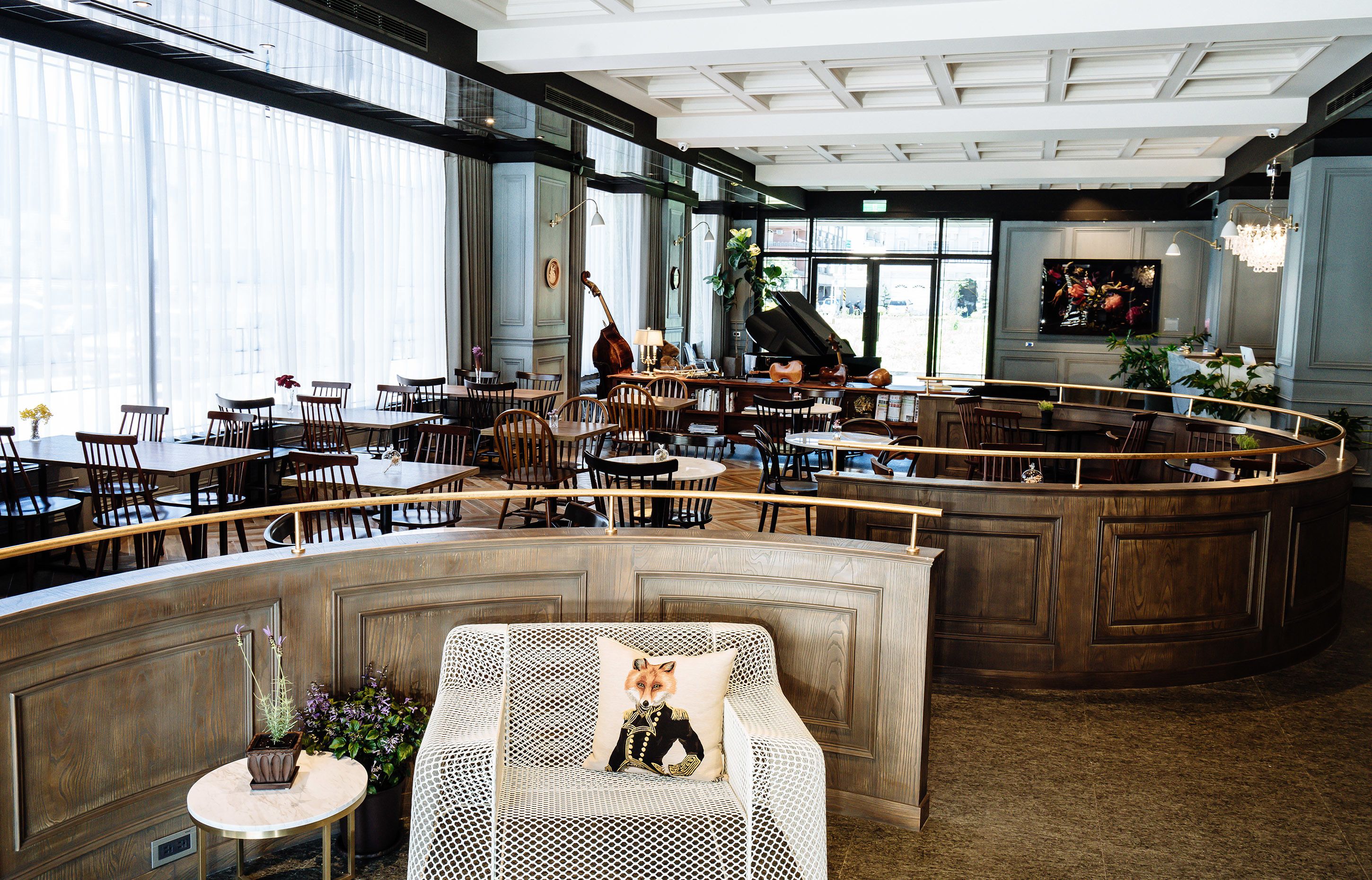 A restaurant with a curved bar, multiple dining tables, and chairs. There is a piano and a guitar in the background.
