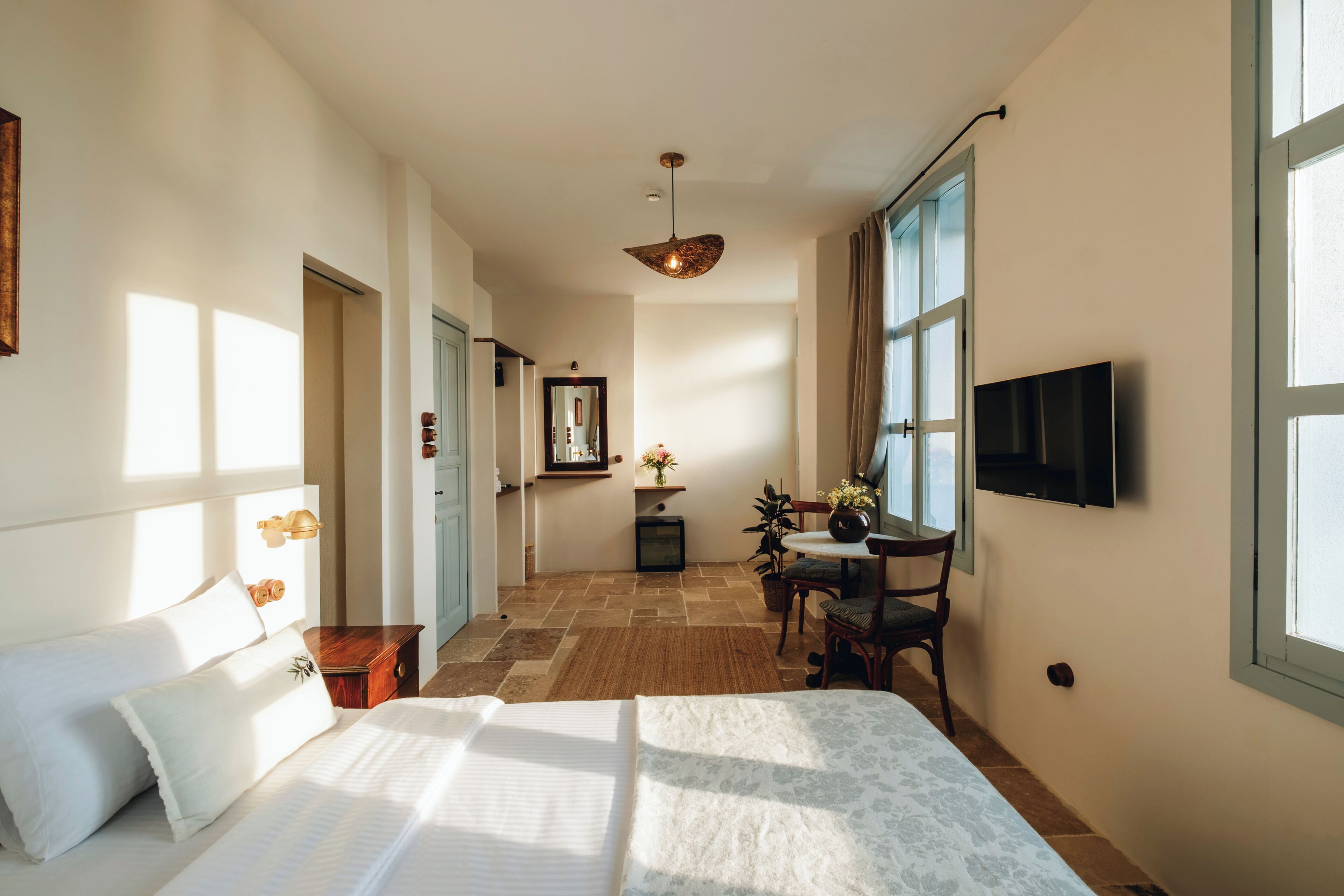 Une chambre d’hôtel avec un lit, un bureau, une chaise, une télévision et une grande fenêtre.