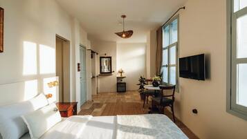 Une chambre d’hôtel avec un lit, un bureau, une chaise, une télévision et une grande fenêtre.
