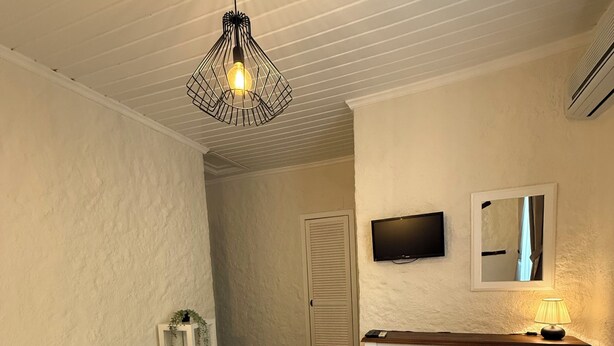 Quarto de hotel com duas camas de solteiro, uma escrivaninha com cadeira, televisão e espelho.