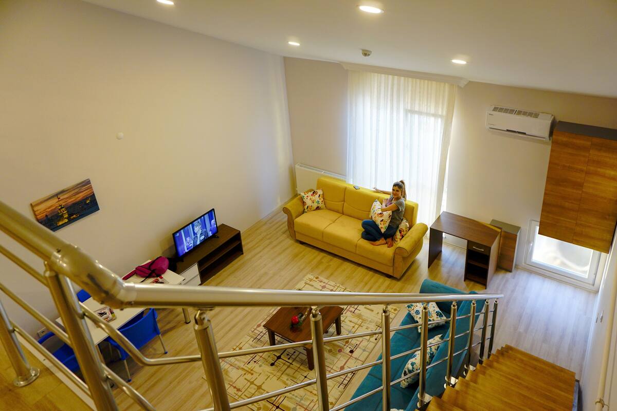 A living room with a sofa, a television, and a staircase.