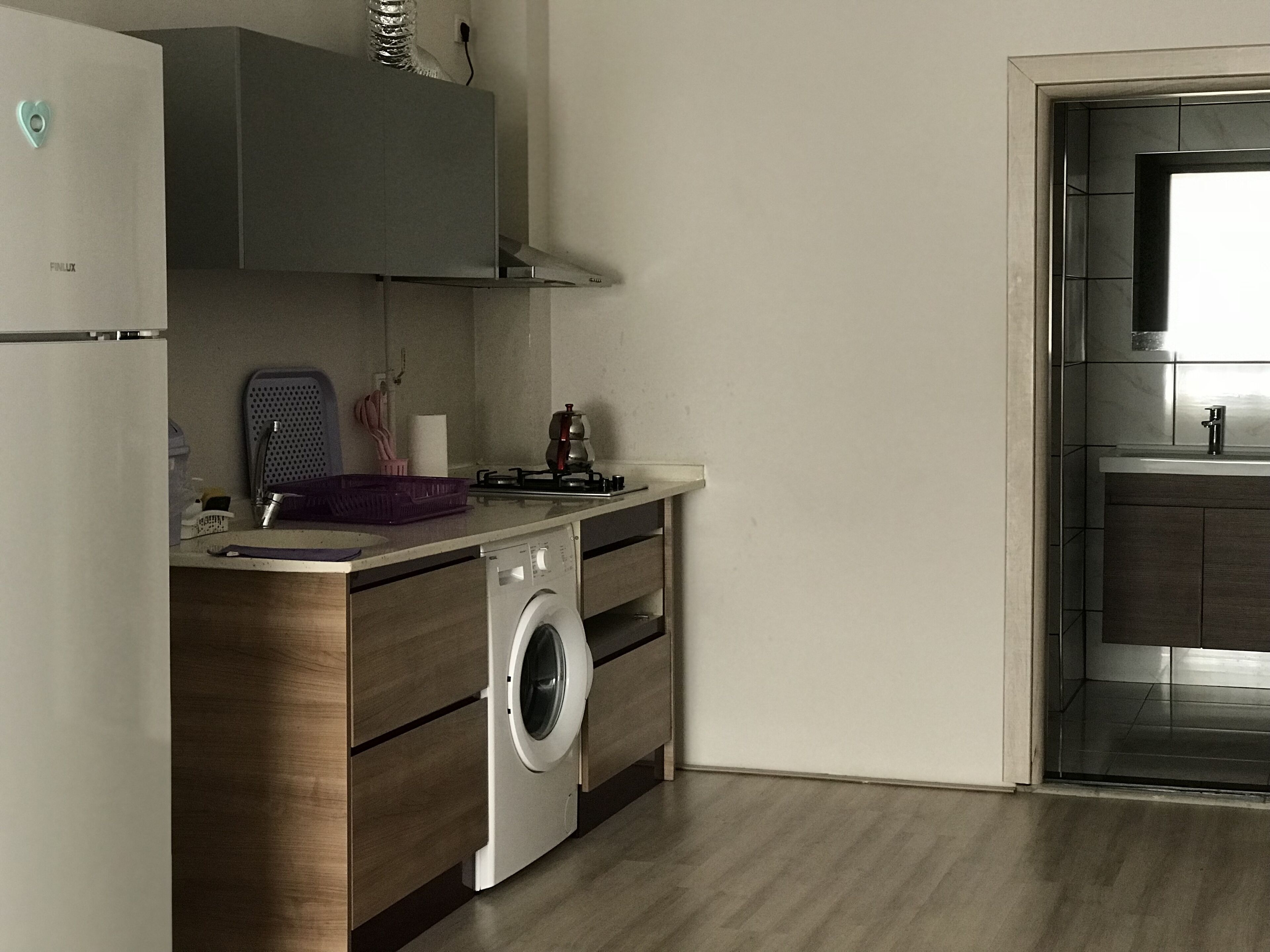 Une cuisine compacte dotée d’un lave-linge intégré, d’un petit coin repas et donnant sur la salle de bain adjacente.