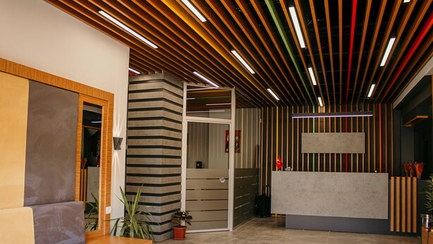 A modern reception area with a reception desk, a seating area with a sofa, and a potted plant. - Hayat Palas (Erzincan)