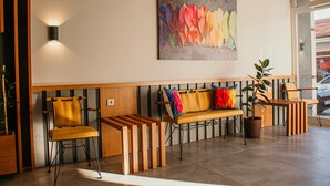 A reception area with a bench, chairs, a wall-mounted light, and a potted plant. - Hayat Palas (Erzincan)