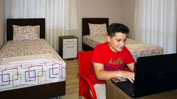 A hotel room with two beds, a desk with a laptop, and a chair.