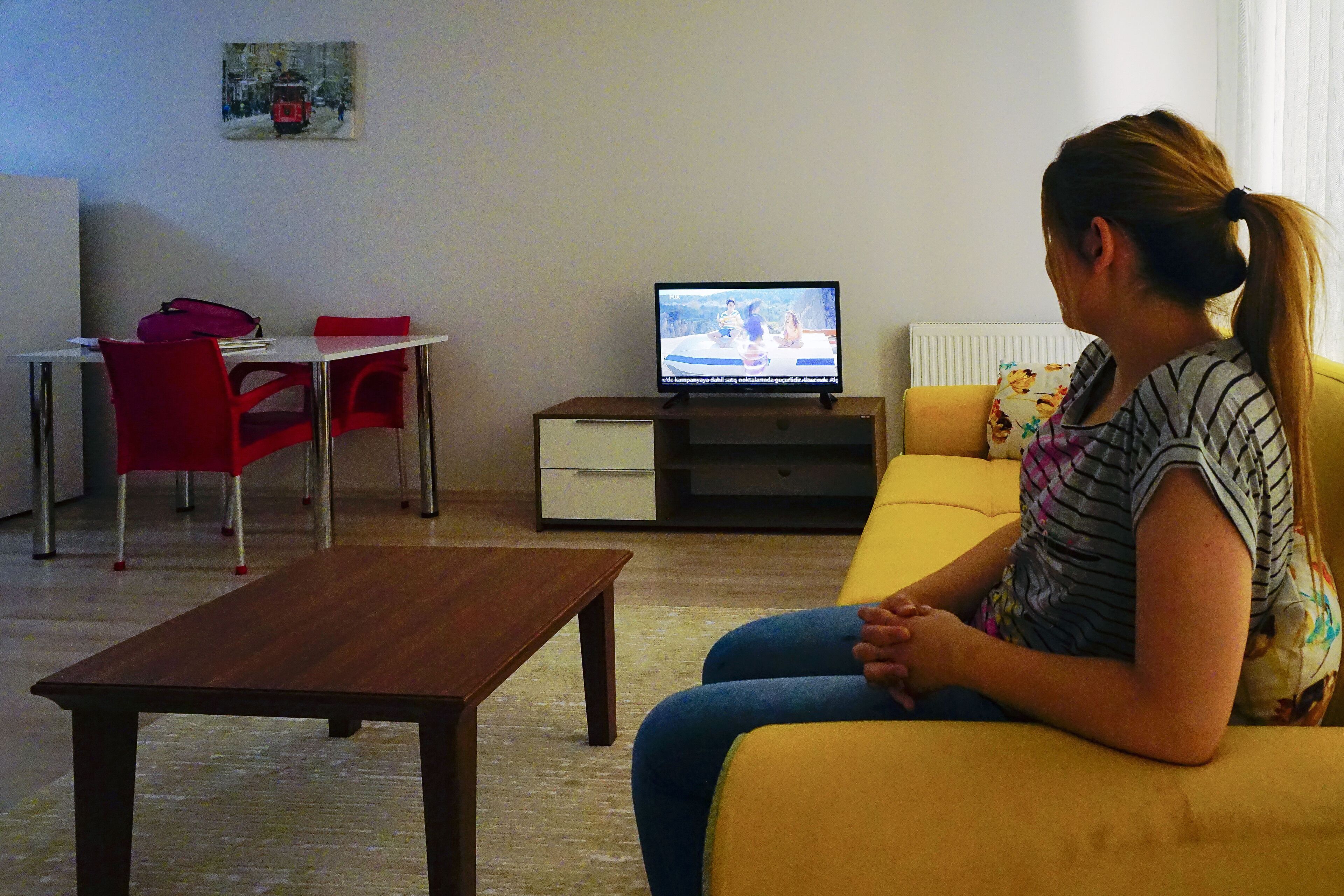 A living room with a sofa, a coffee table, a TV, and a dining area with chairs and a table.