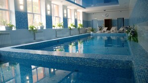 An indoor swimming pool with clear blue water, surrounded by blue-tiled walls and windows. - Fantasia Hotel (Poliana)