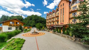 A hotel with a central courtyard, multiple balconies, and a mountain backdrop. - Fantasia Hotel (Poliana)