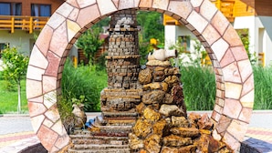 A stone archway with a rustic stone structure and a small fountain in the center. - Fantasia Hotel (Poliana)