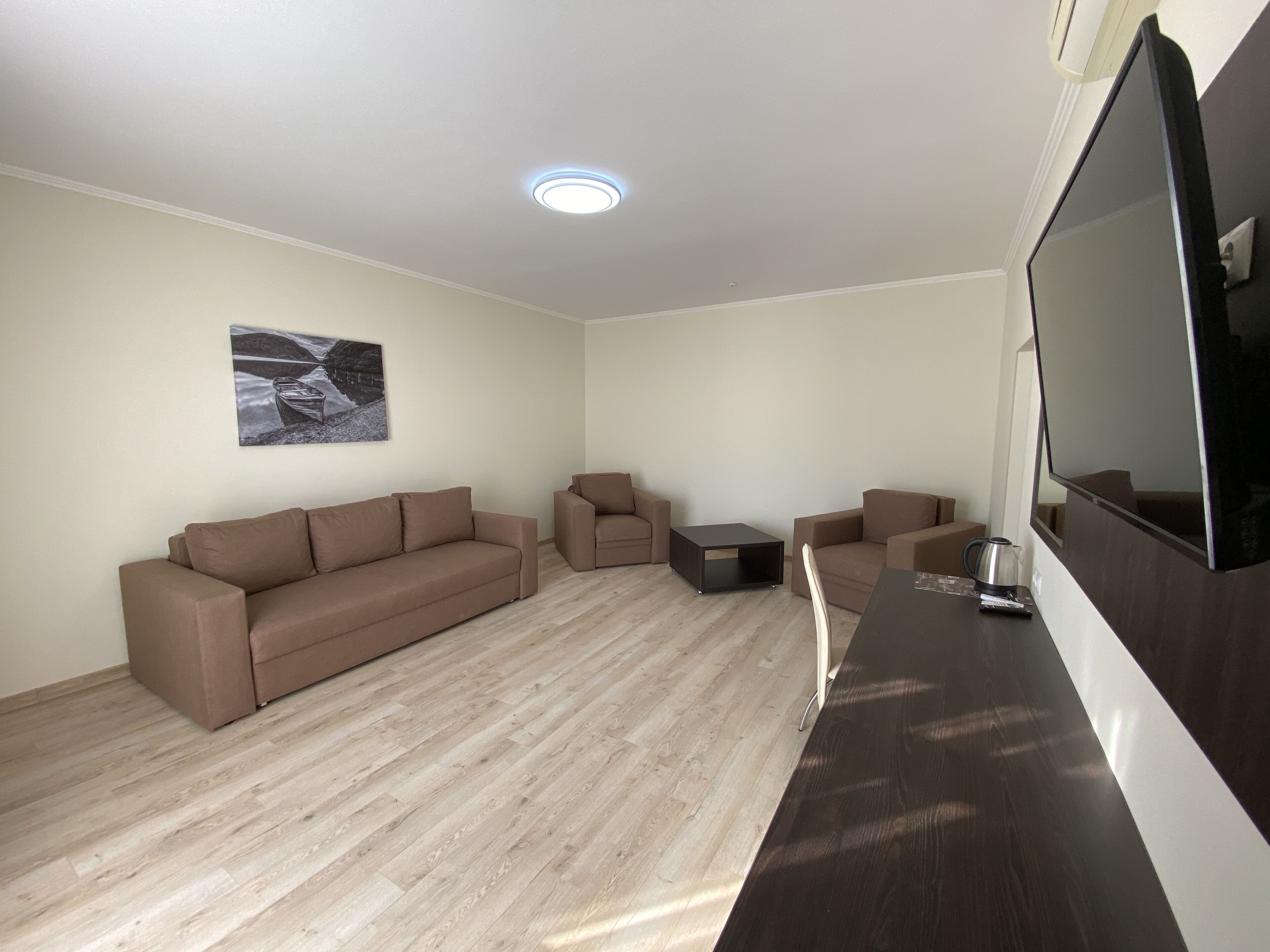 A modern living room with a brown sofa, a small coffee table, and a TV mounted on the wall.