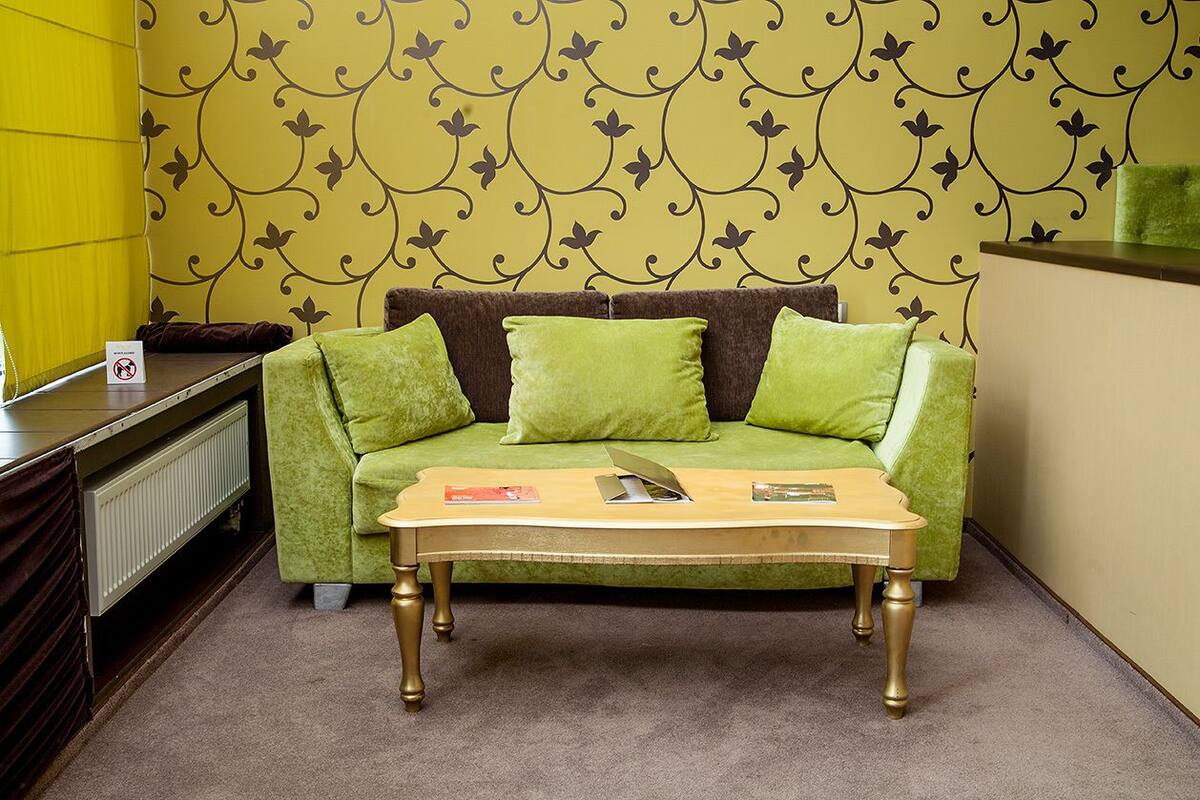 A room with a green sofa, a wooden coffee table, and a radiator.