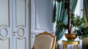 Una habitación con un sillón grande, una mesita con revistas, una planta en maceta y un sofá.