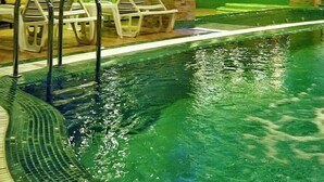 Una piscina interior con sillones de descanso y un tobogán de agua.