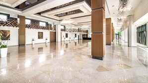 A spacious lobby with a polished floor, modern lighting fixtures, and a high ceiling.