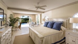 A bedroom with a large bed, a ceiling fan, a TV, a desk, and a chair. - Villa -Westmoreland (Westmoreland)