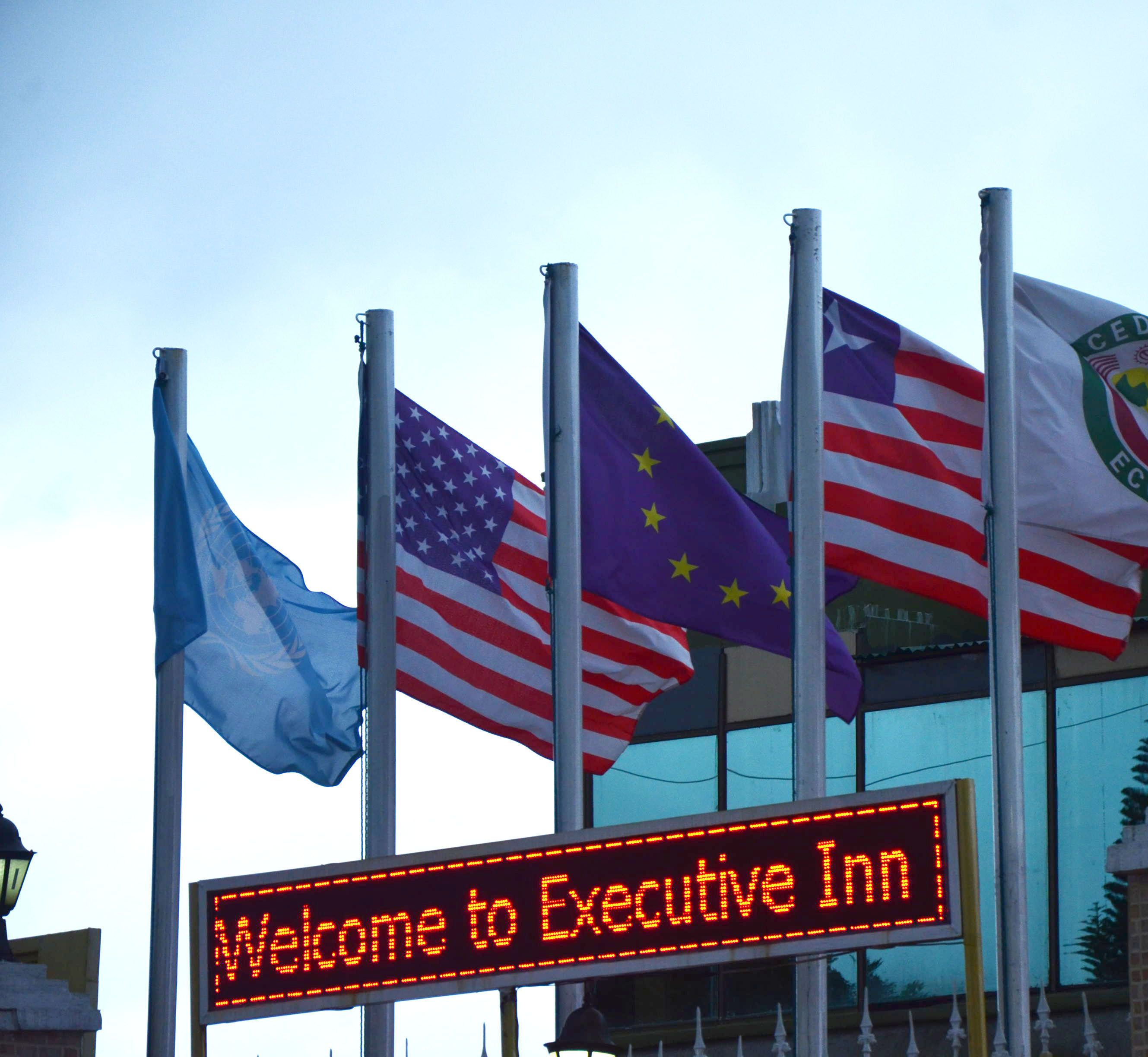 Ein Schild mit der Aufschrift 'Welcome to Executive Inn' und mehreren Flaggen im Vordergrund.