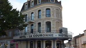 Un hotel con facciata in pietra, numerosi balconi e un cartello con la scritta 'HOTEL - LA COURONNE - HOTEL'.