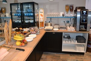 Un bufé de desayuno con diversas opciones de comida, una máquina de café y vasos.