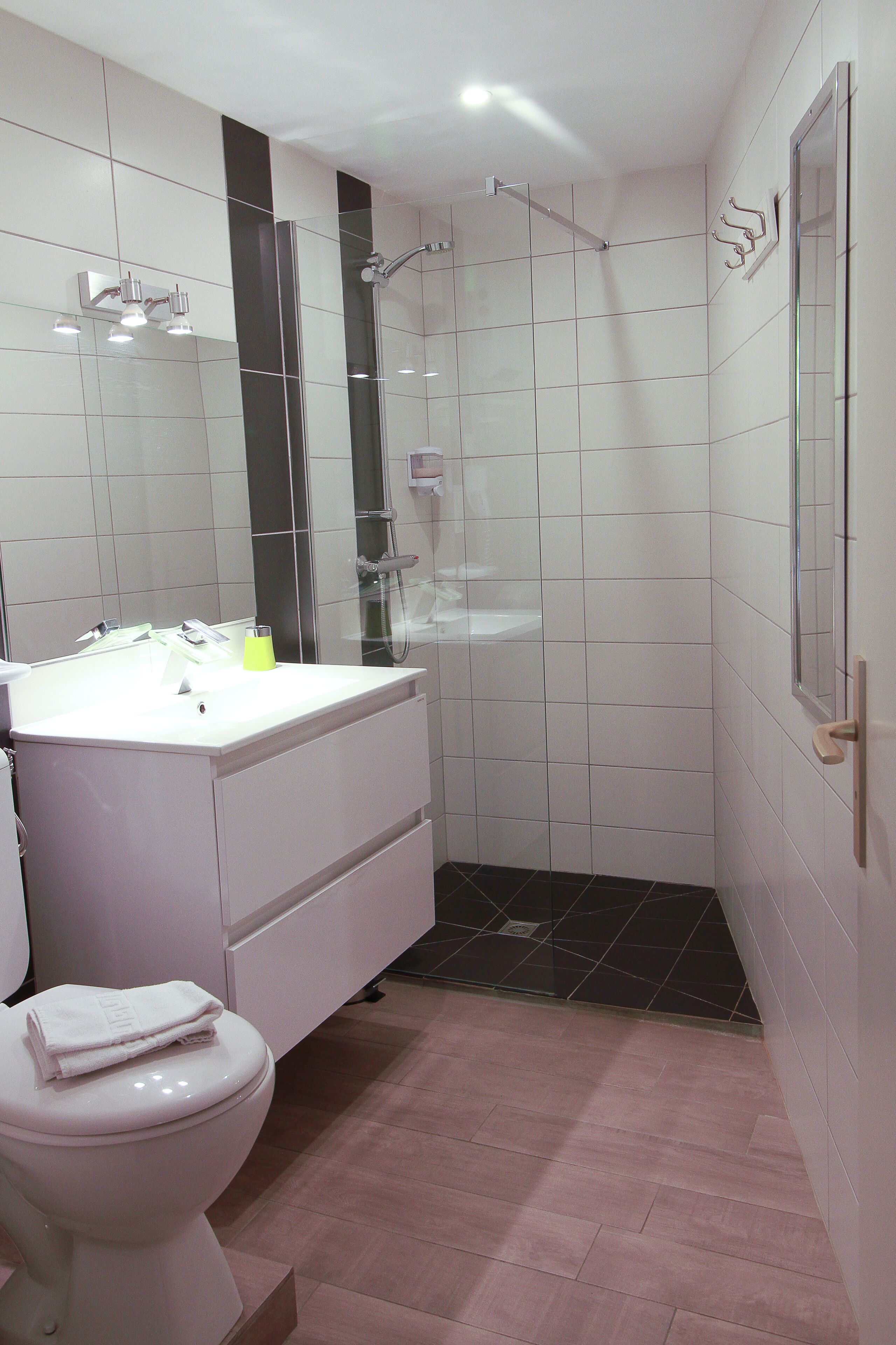 A modern bathroom with a white sink, mirror, and toilet.