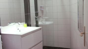 A modern bathroom with a white sink, mirror, and toilet.