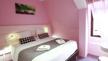Habitación de hotel en tonos rosas con una cama bien hecha, un cuadro en la pared y una ventana con cortinas.