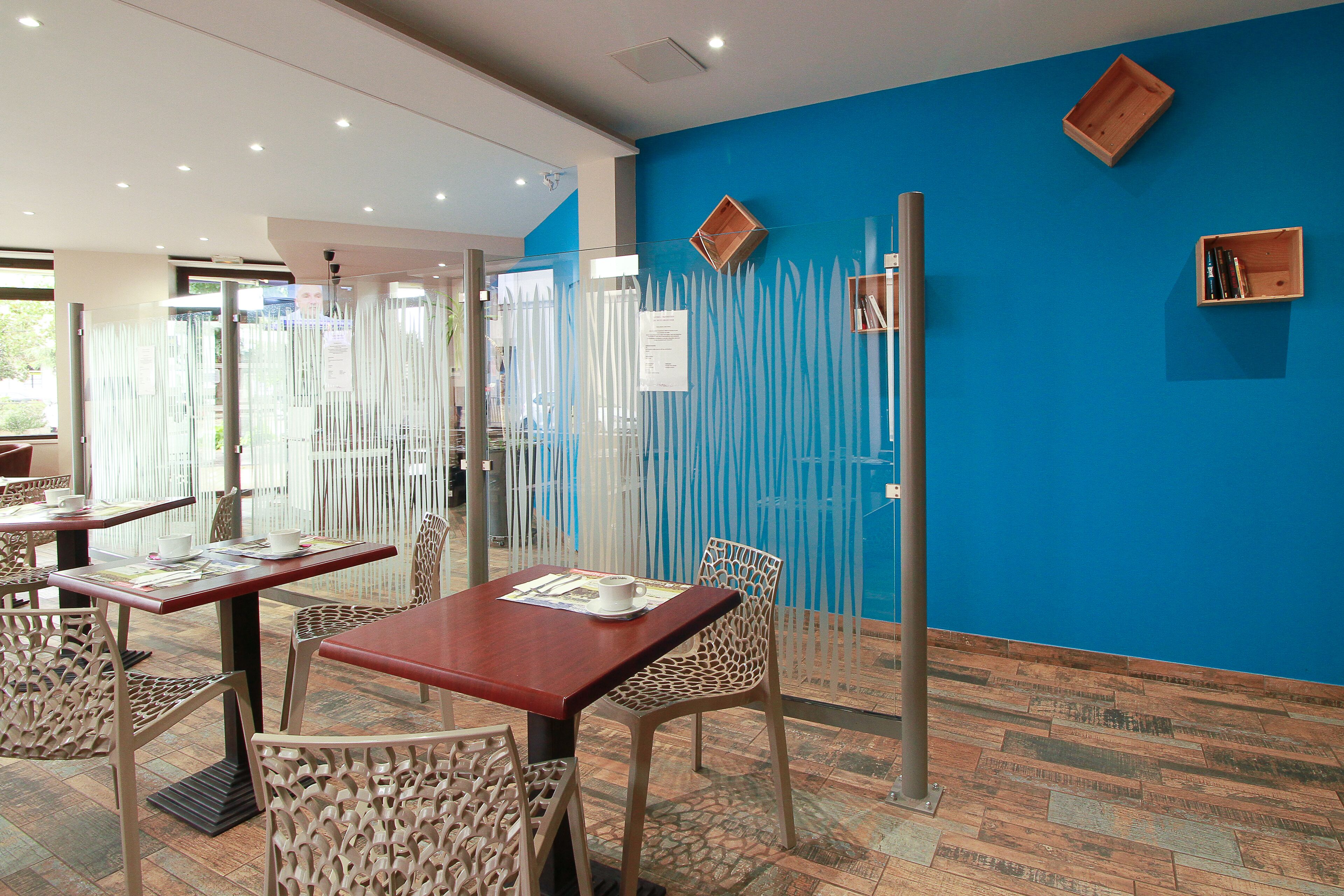 A restaurant with tables and chairs, a blue wall, and a wooden floor.