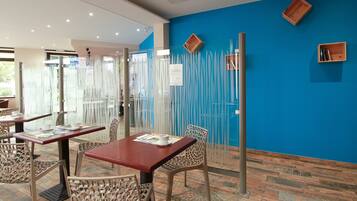 Een restaurant met tafels en stoelen, een blauwe wand en een houten vloer.