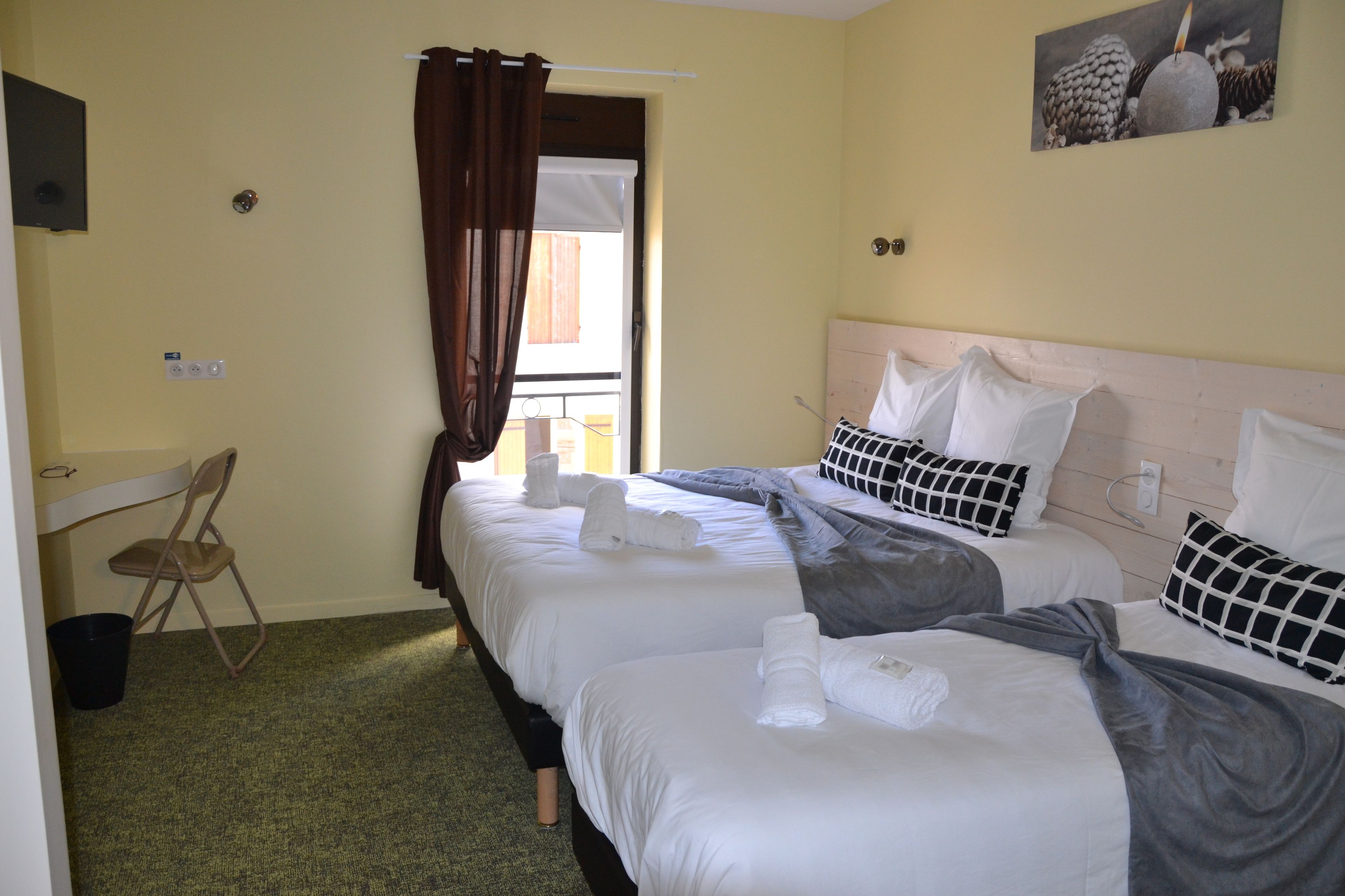 A hotel room with two beds, a chair, a window with curtains, and a painting on the wall.