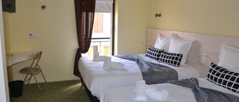 A hotel room with two beds, a chair, a window with curtains, and a painting on the wall.