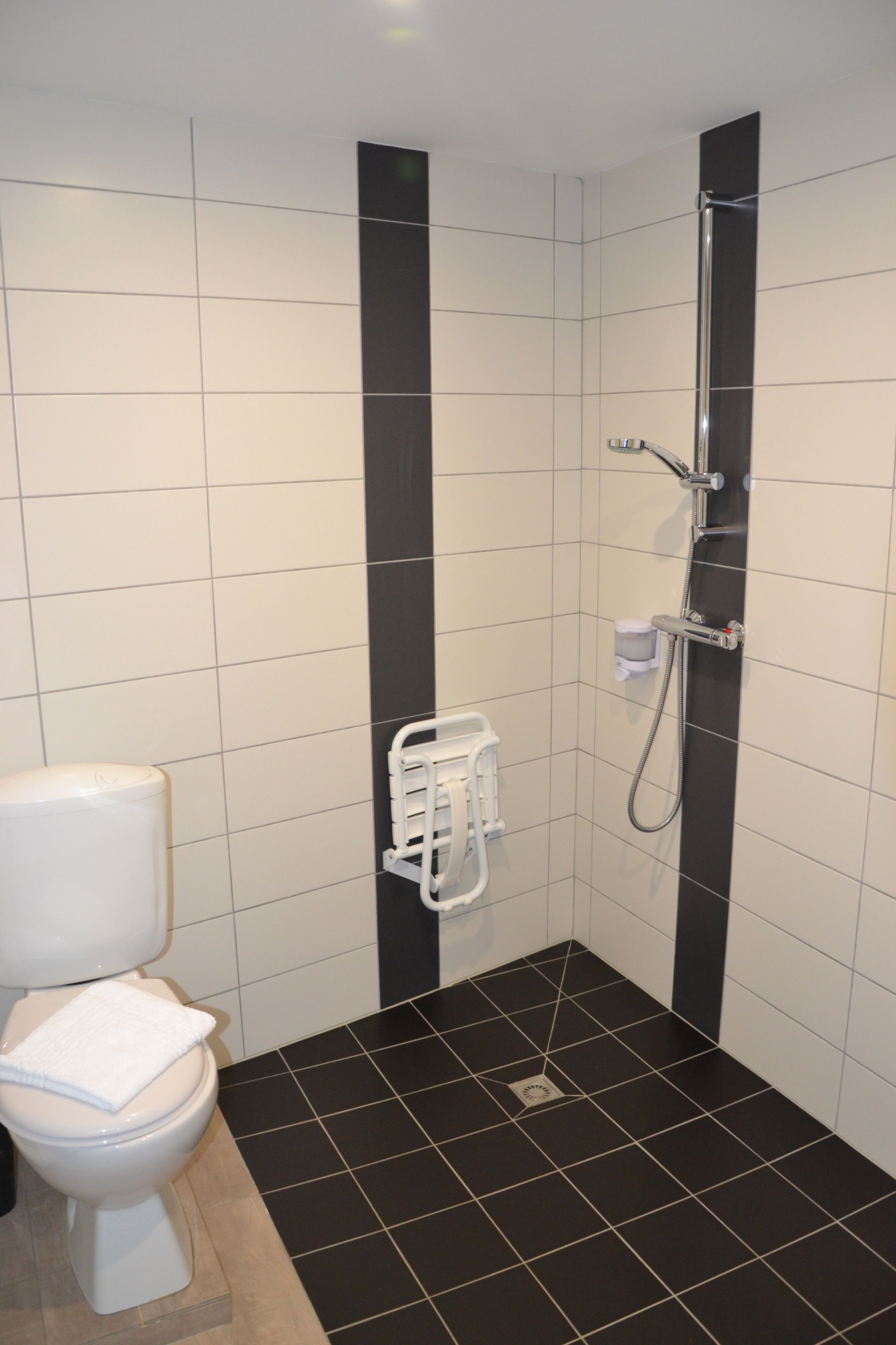 A small, modern bathroom with a toilet, a shower, and a hand dryer.