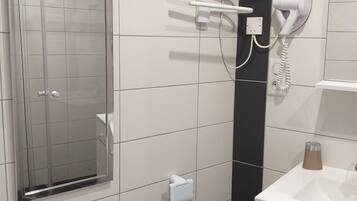A bathroom with a toilet, a sink, a hairdryer, and a mirror.