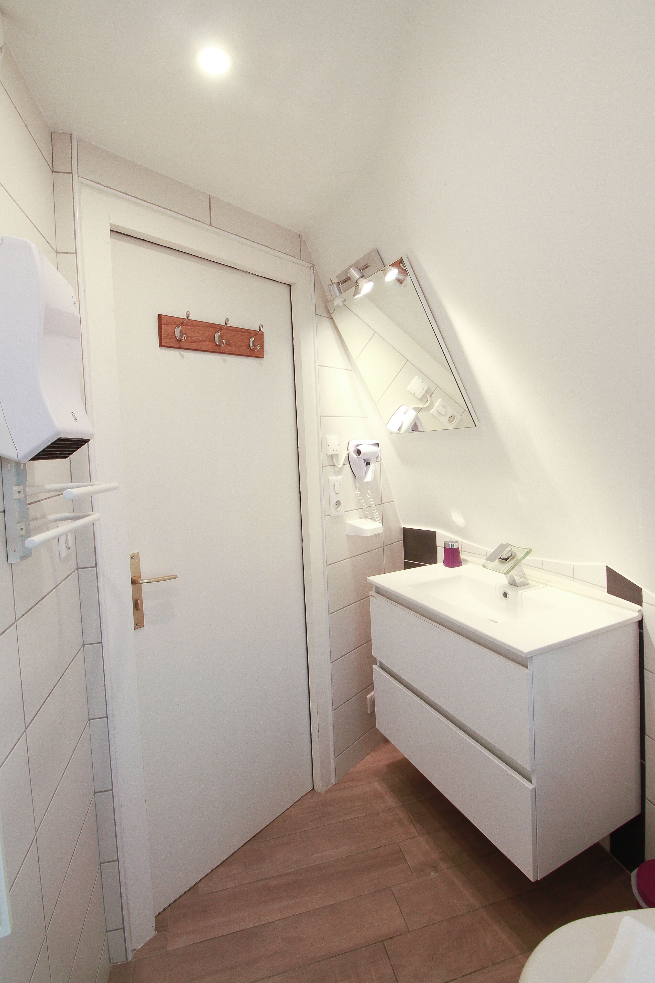 A modern bathroom with a white vanity, a mirror, and a towel rack.
