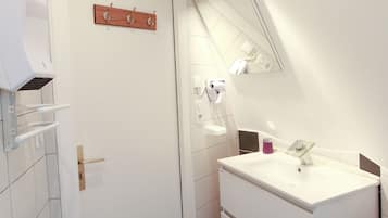 A modern bathroom with a white vanity, a mirror, and a towel rack.