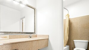 A bathroom with a sink, mirror, toilet, and shower curtain. - Capitol Inn And Suites (Montgomery)