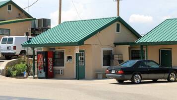 A building with a green roof, a Coca-Cola vending machine, and a sign indicating an office.