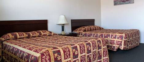 A hotel room with two beds, a nightstand, a lamp, and a painting on the wall.