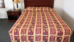 Una cama bien hecha con una colcha estampada de flores y un cabecero de madera.