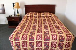 Una cama bien hecha con una colcha estampada de flores y un cabecero de madera.